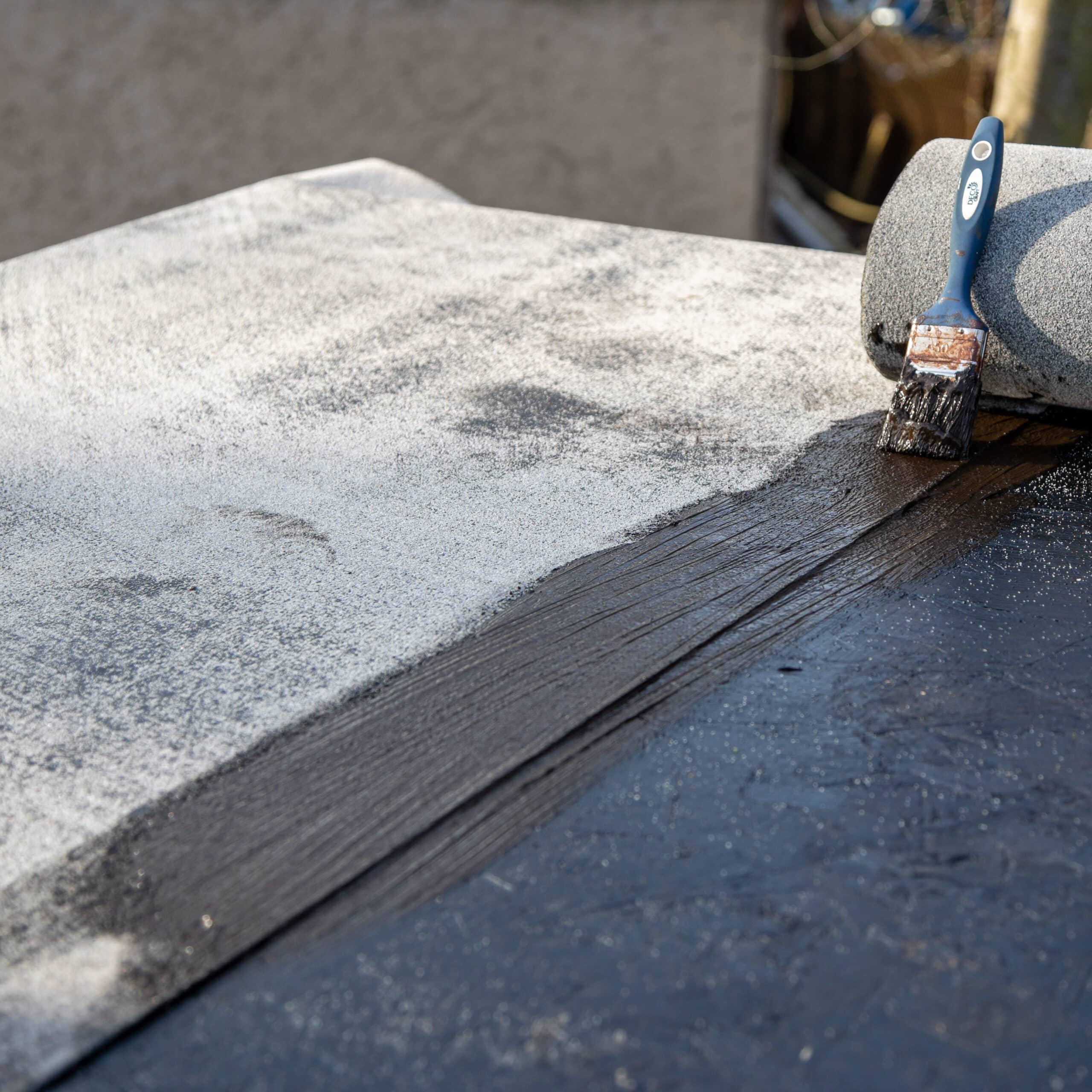 Étanchéité Toit Plat : Application de Revêtement Bitume Application d'un produit d'étanchéité bitumineux sur un toit plat avec pinceau et rouleau de rénovation.